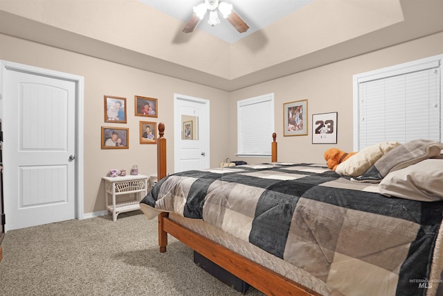 carpeted bedroom featuring a tray ceiling and ceiling fan