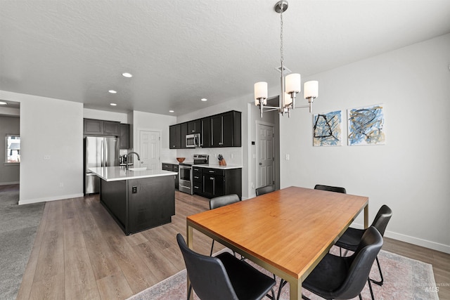 dining room with sink, hardwood / wood-style floors, a textured ceiling, and an inviting chandelier