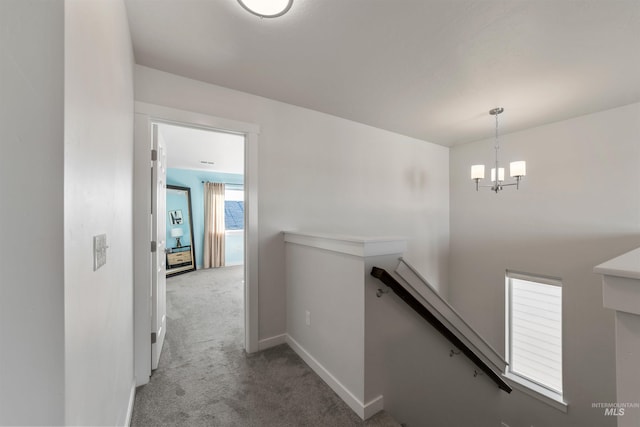 hall featuring an inviting chandelier and carpet flooring