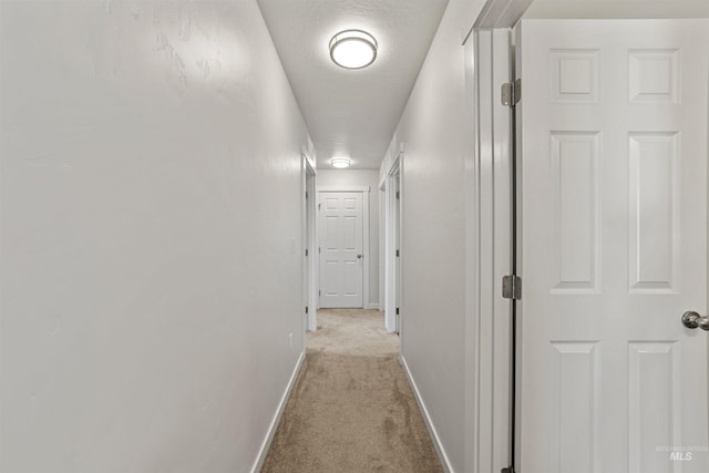 hallway with light colored carpet and a textured ceiling