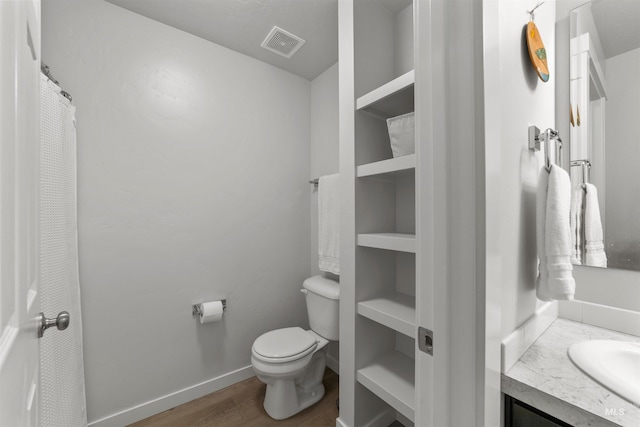 bathroom featuring vanity, wood-type flooring, and toilet