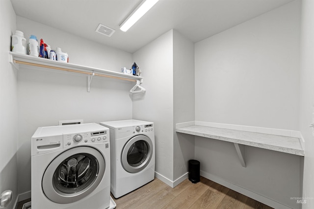 clothes washing area with washing machine and dryer and hardwood / wood-style floors