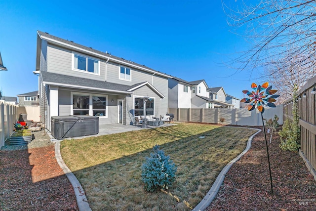 rear view of house featuring a hot tub, a lawn, and a patio area