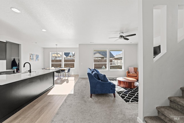 living room with sink, a wealth of natural light, a textured ceiling, and light wood-type flooring