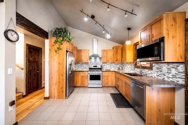 kitchen featuring wall chimney range hood, sink, stainless steel appliances, pendant lighting, and decorative backsplash