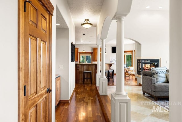 4553 N Arrow Crest Way, Boise, ID 83703 - hall with healthy amount of natural light, a textured ceiling, ornate columns, wood finished floors, and arched walkways