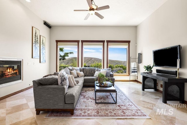 4553 N Arrow Crest Way, Boise, ID 83703 - living area featuring a glass covered fireplace, a ceiling fan, baseboards, and light tile patterned flooring