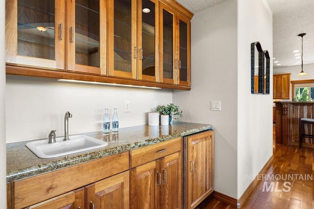 4553 N Arrow Crest Way, Boise, ID 83703 - bar area featuring a sink, dark wood-type flooring, pendant lighting, a textured ceiling, and baseboards