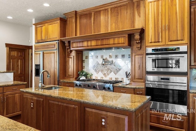 4553 N Arrow Crest Way, Boise, ID 83703 - kitchen with a sink, brown cabinetry, backsplash, light stone countertops, and recessed lighting