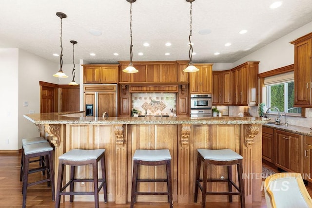 4553 N Arrow Crest Way, Boise, ID 83703 - kitchen with paneled fridge, a sink, recessed lighting, dark wood-style floors, and a large island