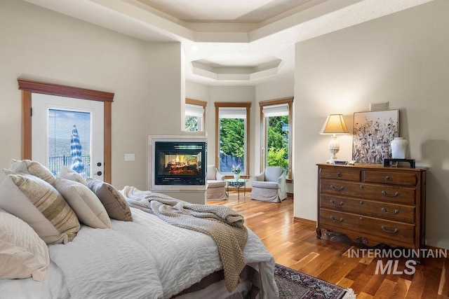 4553 N Arrow Crest Way, Boise, ID 83703 - bedroom with a tray ceiling, a multi sided fireplace, wood finished floors, and access to exterior
