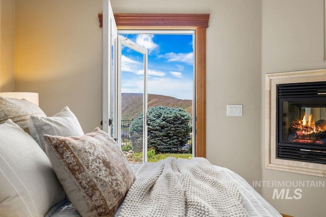 4553 N Arrow Crest Way, Boise, ID 83703 - bedroom featuring a glass covered fireplace, a mountain view, multiple windows, and access to outside