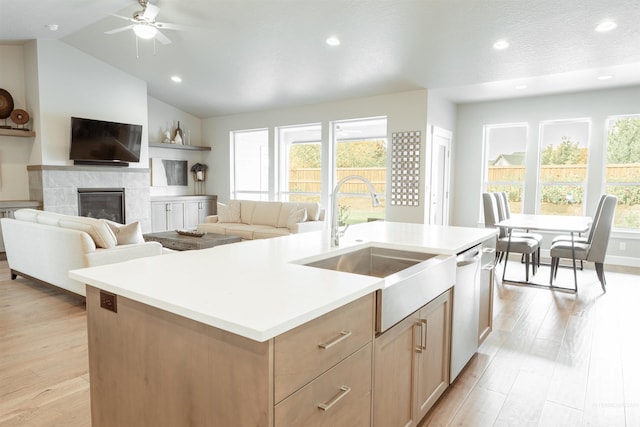 kitchen with light countertops, a center island with sink, light wood-style flooring, and a sink