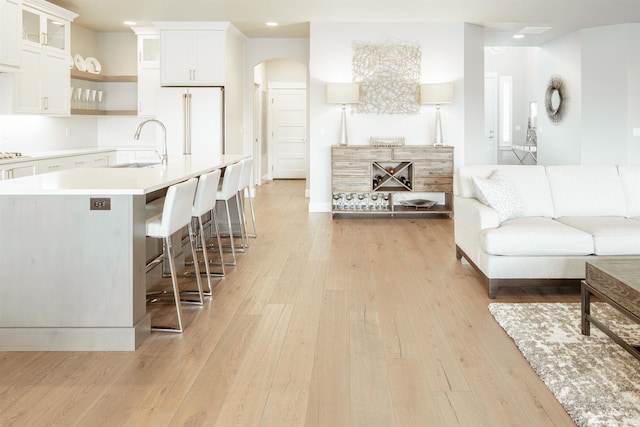 living area with recessed lighting, light wood-style flooring, and arched walkways