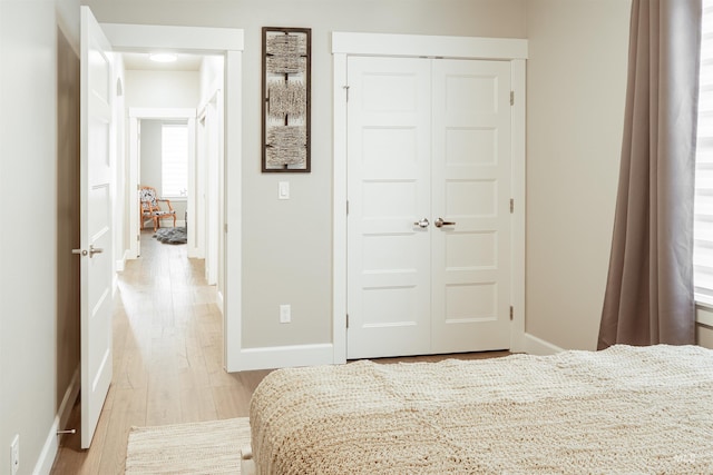 bedroom with a closet, wood finished floors, and baseboards