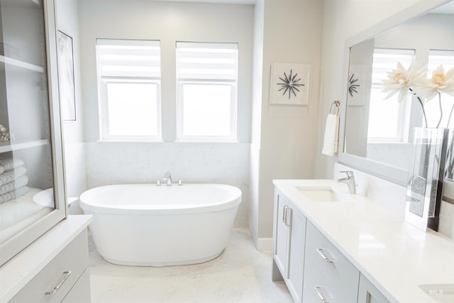 bathroom with marble finish floor, a soaking tub, and vanity