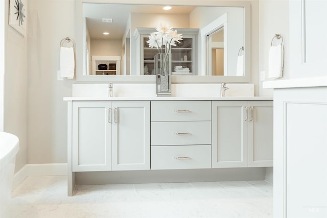 bathroom with baseboards, recessed lighting, double vanity, and a sink