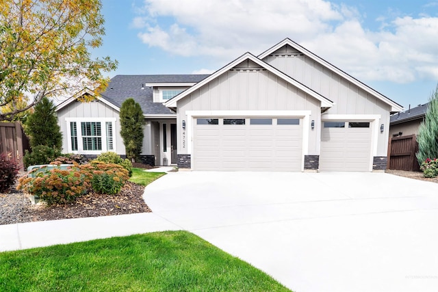 view of front of house with board and batten siding, concrete driveway, stone siding, fence, and a garage