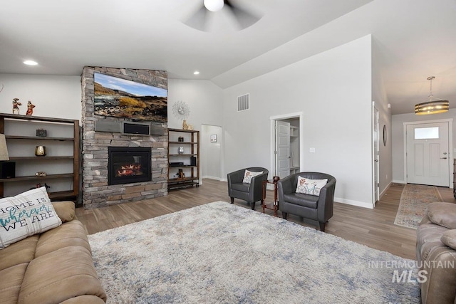 living area featuring visible vents, wood finished floors, baseboards, ceiling fan, and vaulted ceiling