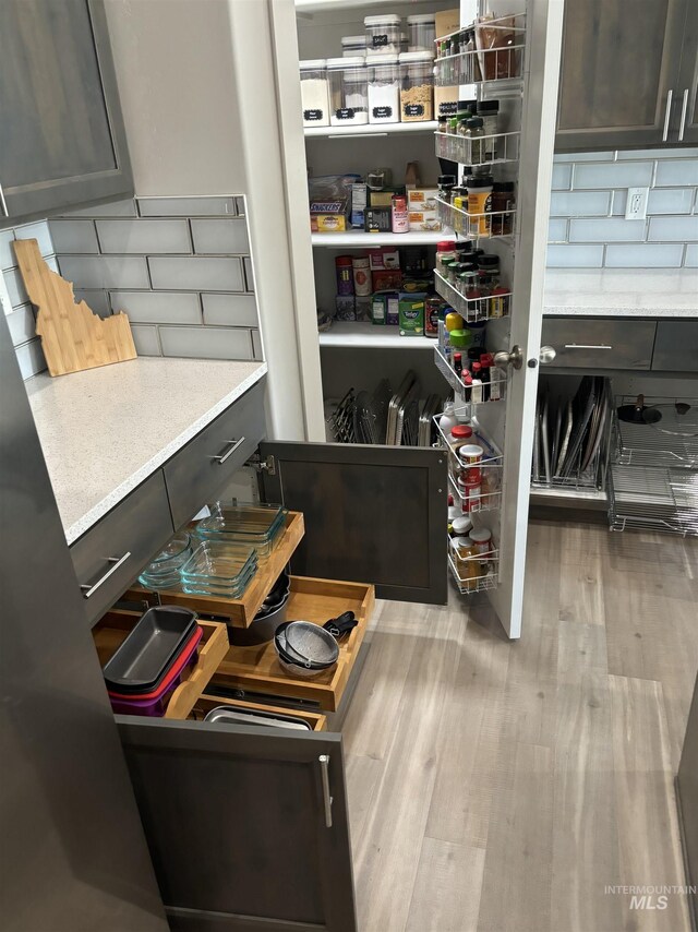 kitchen with appliances with stainless steel finishes, dark brown cabinets, decorative backsplash, and light stone countertops