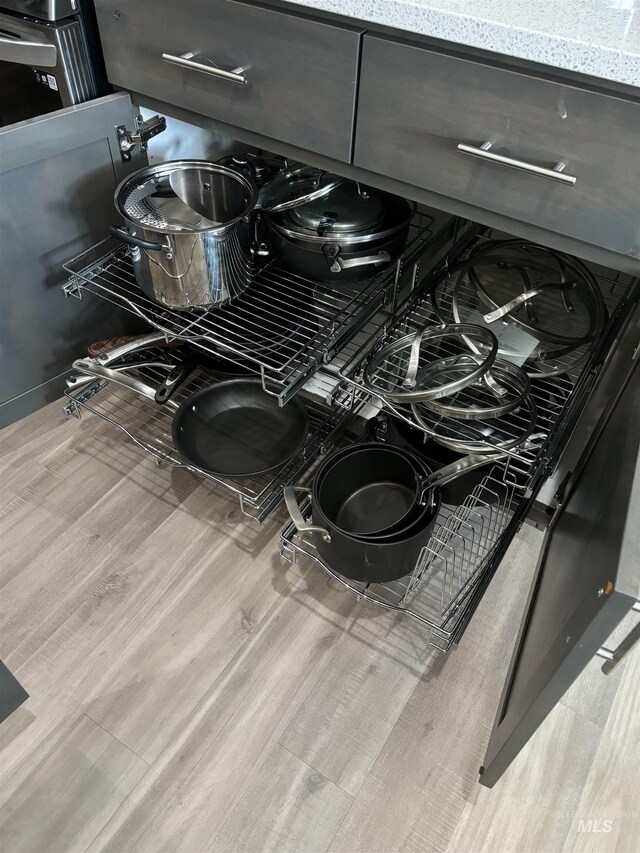 kitchen featuring dark brown cabinetry, light hardwood / wood-style flooring, light stone countertops, tasteful backsplash, and stainless steel appliances