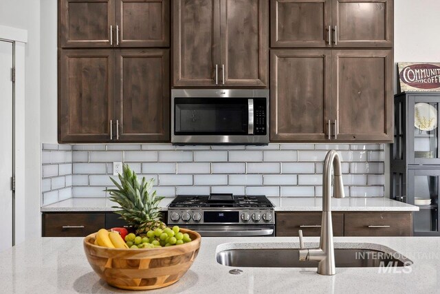 kitchen with decorative light fixtures, tasteful backsplash, a center island with sink, lofted ceiling, and dark hardwood / wood-style flooring