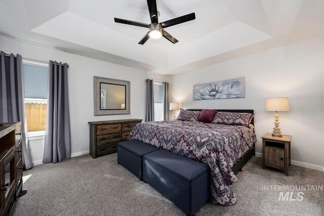 bedroom with a tray ceiling, ceiling fan, ensuite bath, and light carpet