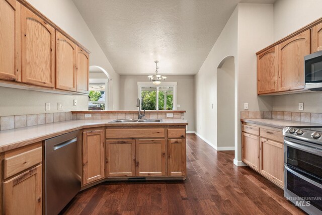 613 E Sable Ridge Dr, Kuna, ID 83634 - kitchen featuring appliances with stainless steel finishes, a sink, lofted ceiling, a peninsula, and arched walkways
