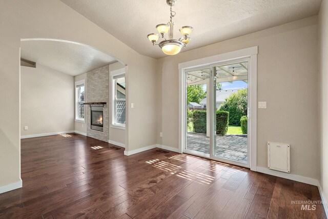 613 E Sable Ridge Dr, Kuna, ID 83634 - unfurnished living room with arched walkways, healthy amount of natural light, a chandelier, hardwood / wood-style flooring, and a textured ceiling