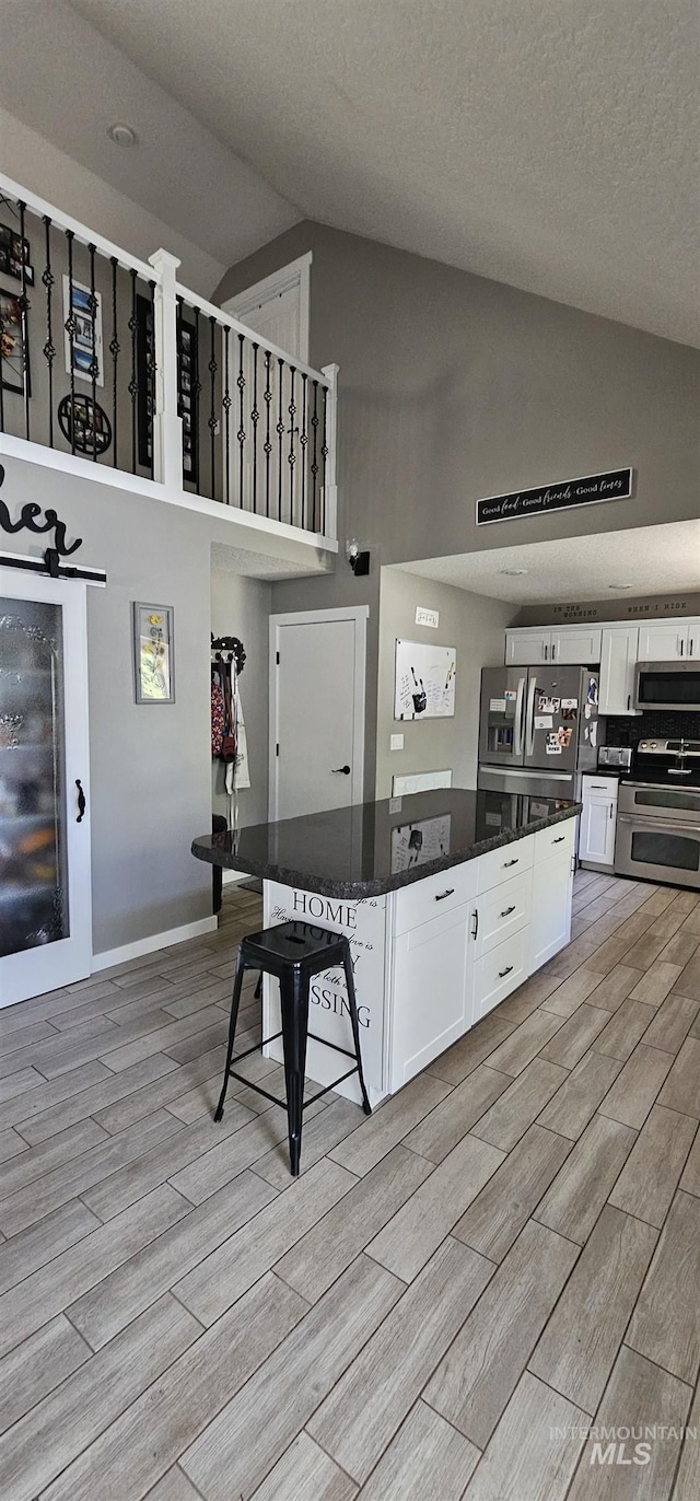 1122 N Roper Pl, Meridian, ID 83642 - kitchen featuring appliances with stainless steel finishes, high vaulted ceiling, white cabinetry, light wood-type flooring, and a kitchen island