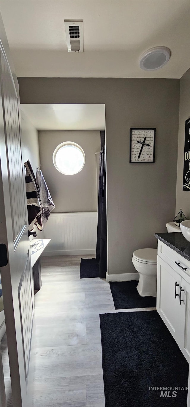 1122 N Roper Pl, Meridian, ID 83642 - bathroom with vanity, toilet, wood finished floors, baseboards, and a shower with curtain