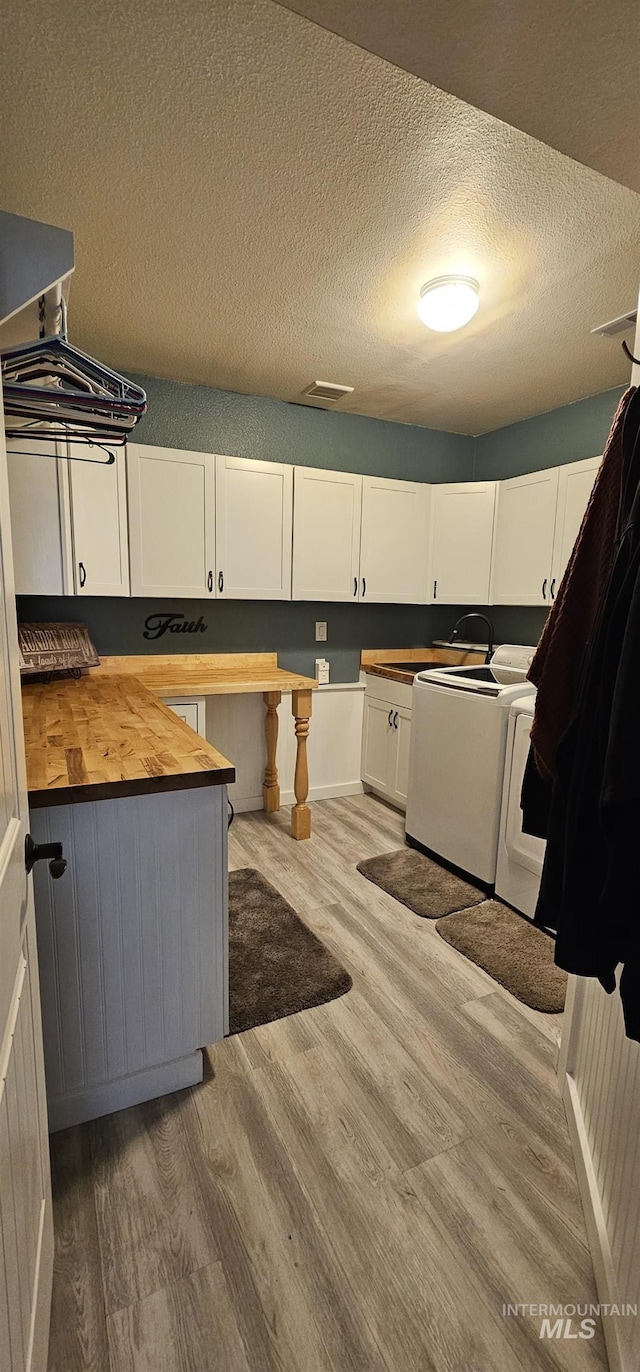 1122 N Roper Pl, Meridian, ID 83642 - kitchen featuring butcher block countertops, washer and clothes dryer, a textured ceiling, light wood-style floors, and white cabinetry