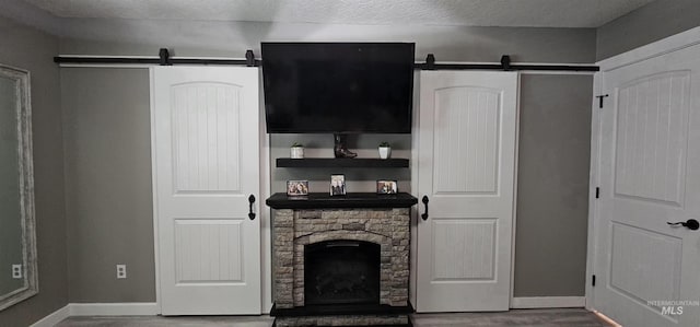 1122 N Roper Pl, Meridian, ID 83642 - living area featuring a barn door, baseboards, wood finished floors, a fireplace, and a textured ceiling