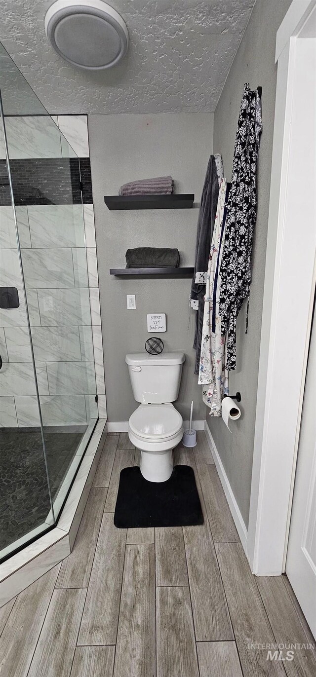 1122 N Roper Pl, Meridian, ID 83642 - bathroom featuring wood finished floors, a shower stall, toilet, and baseboards