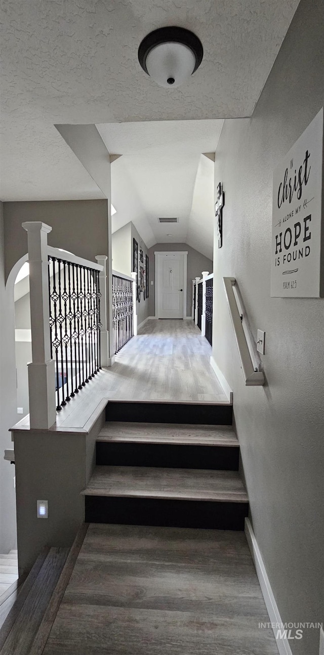 1122 N Roper Pl, Meridian, ID 83642 - stairway featuring baseboards, wood finished floors, lofted ceiling, a textured ceiling, and arched walkways
