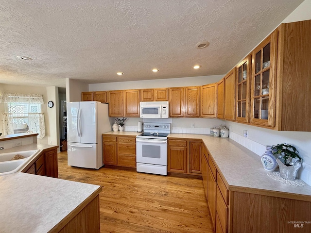 2361 N Pollard Ln, Star, ID 83669 - kitchen featuring white appliances, brown cabinets, a textured ceiling, light wood-style floors, and glass insert cabinets