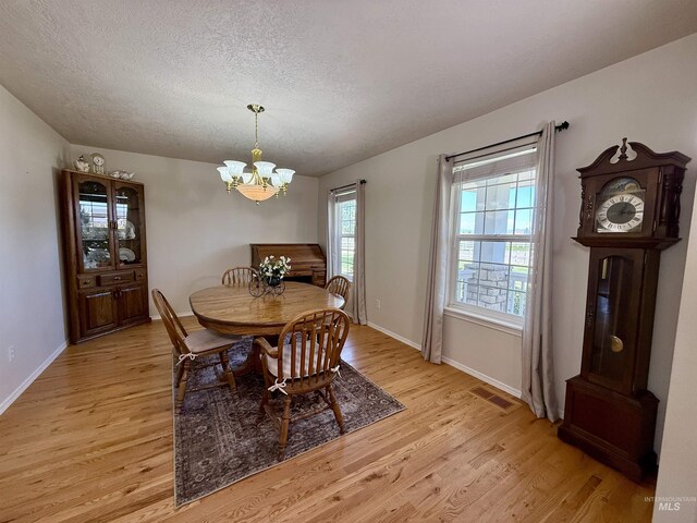 2361 N Pollard Ln, Star, ID 83669 - dining space featuring light wood-type flooring, a chandelier, a textured ceiling, and baseboards