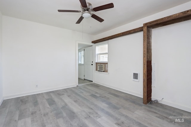 unfurnished room with baseboards, visible vents, a wall unit AC, ceiling fan, and wood finished floors