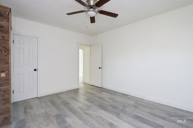 spare room featuring wood finished floors, baseboards, and a ceiling fan