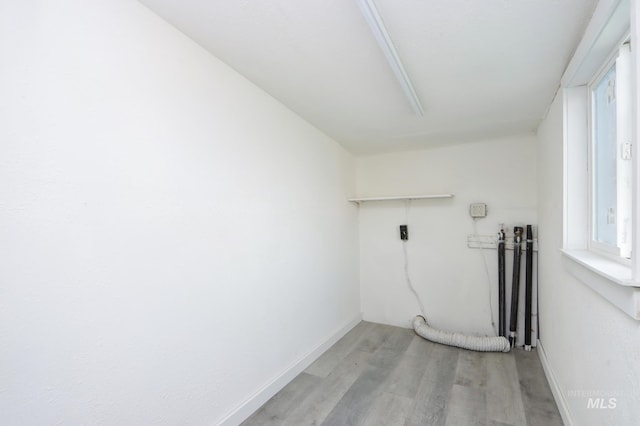 clothes washing area featuring light wood-style flooring, laundry area, and baseboards