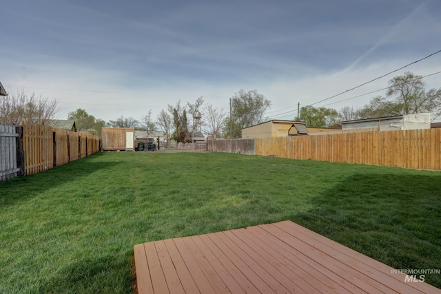 view of yard with a fenced backyard, an outdoor structure, and a storage unit
