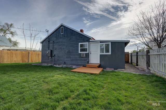 rear view of property with a fenced backyard and a lawn