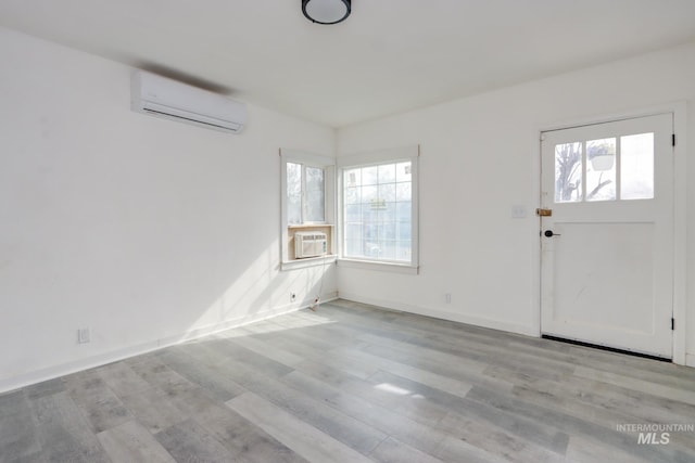 entrance foyer with a wall mounted AC, wood finished floors, baseboards, and a wealth of natural light
