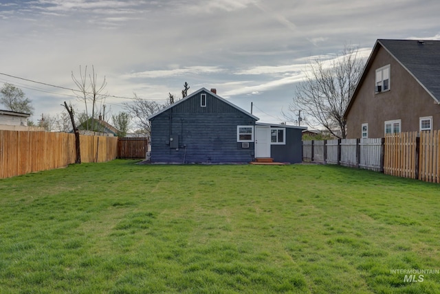 rear view of house featuring a yard, entry steps, and a fenced backyard