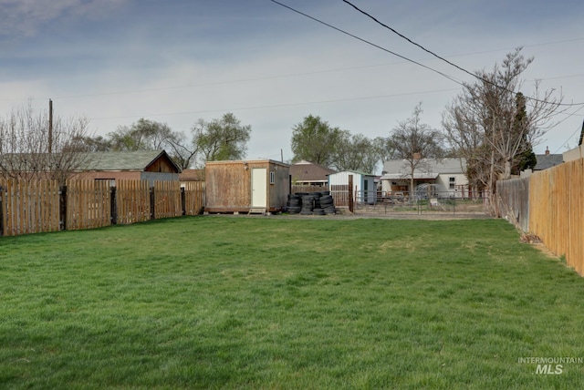 view of yard with a storage shed, an outbuilding, and a fenced backyard