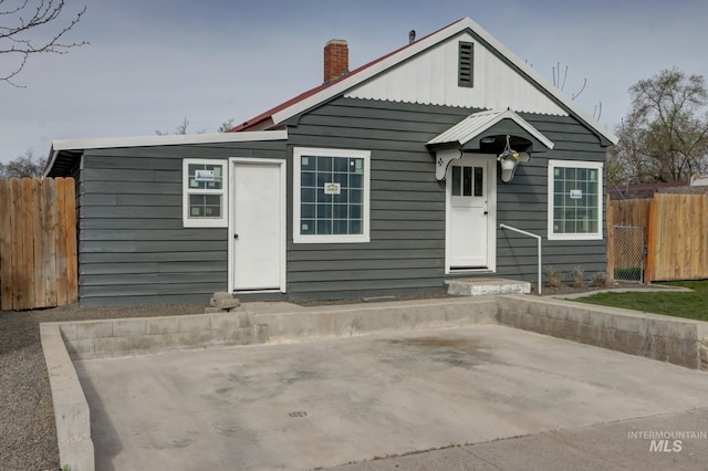 bungalow-style house with a patio, fence, and a chimney