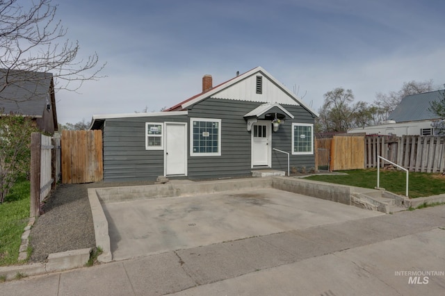 bungalow-style house with entry steps, fence, and a chimney