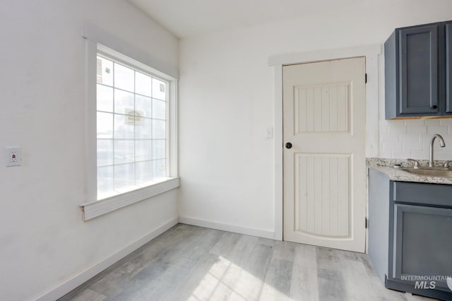 unfurnished dining area with a sink, baseboards, and light wood-style floors
