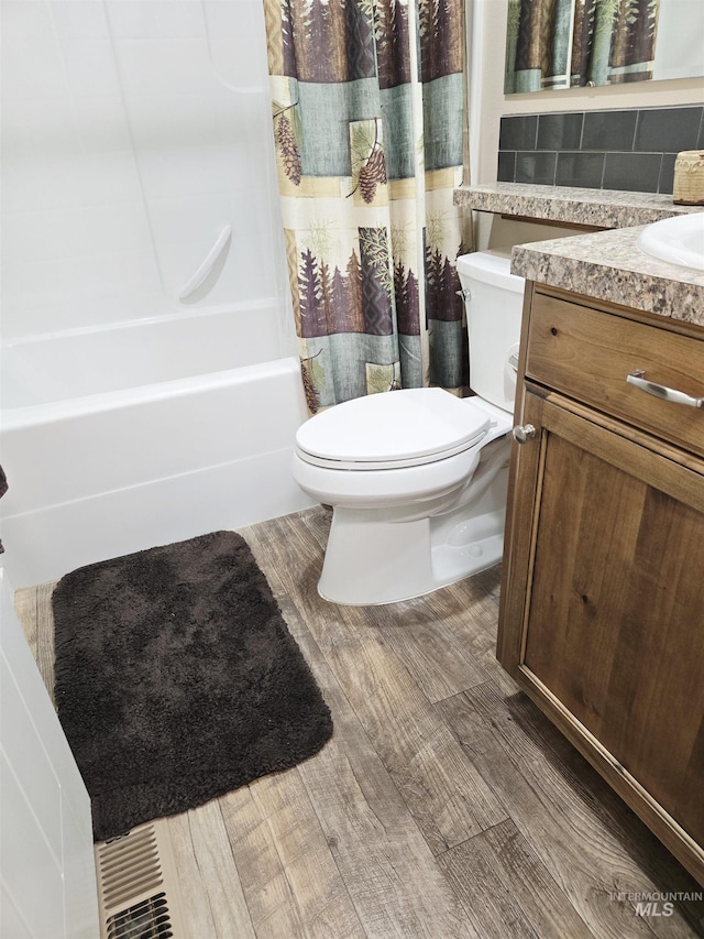 2716 Dogwood Ave, Fruitland, ID 83619 - full bathroom with toilet, shower / tub combo with curtain, wood finished floors, vanity, and backsplash