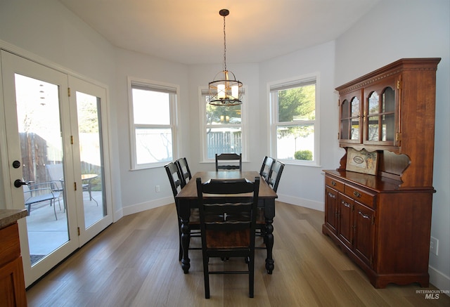 dining space with baseboards, a chandelier, and light wood finished floors